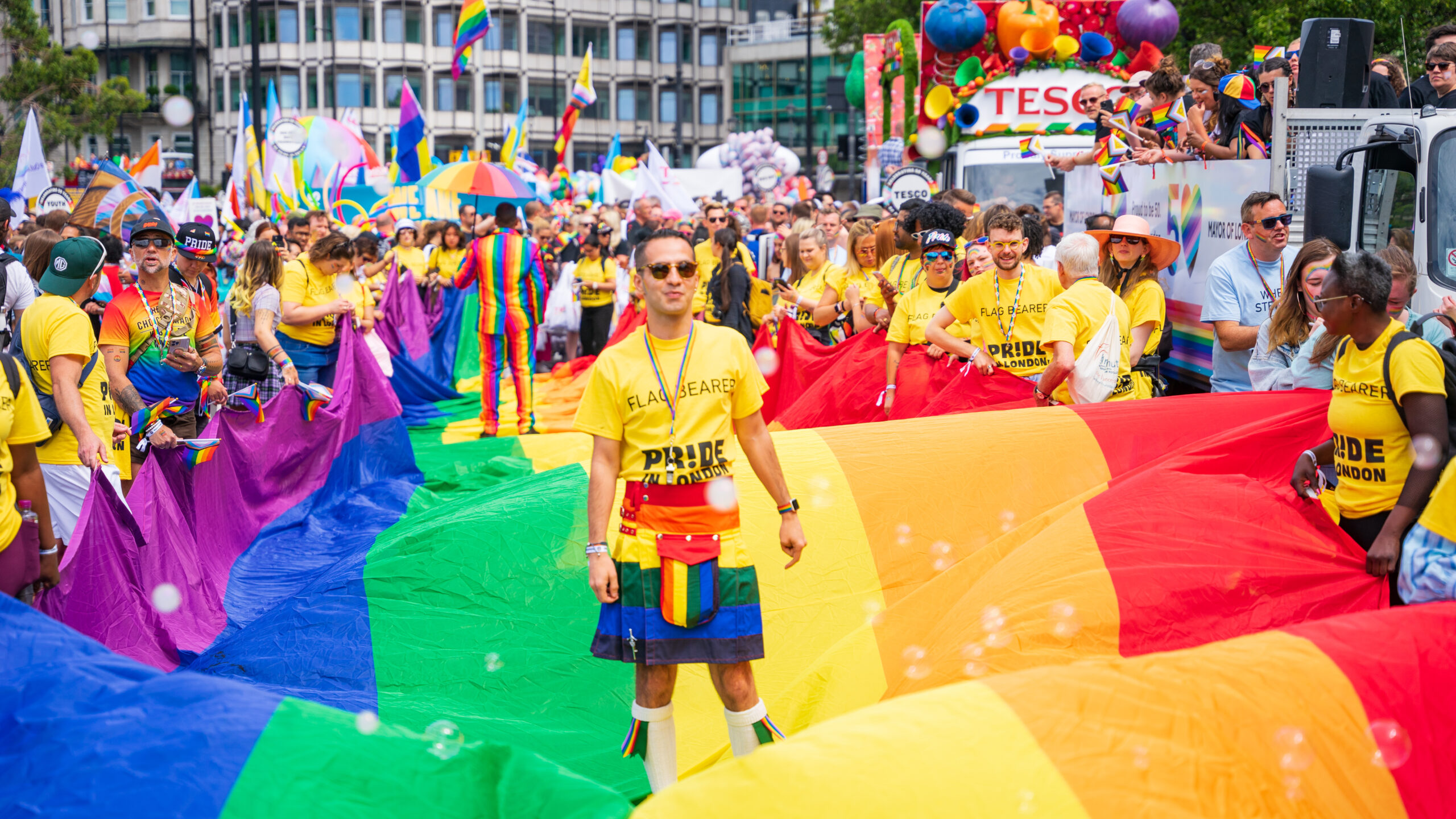 A crowd of people with a large rainbow flag