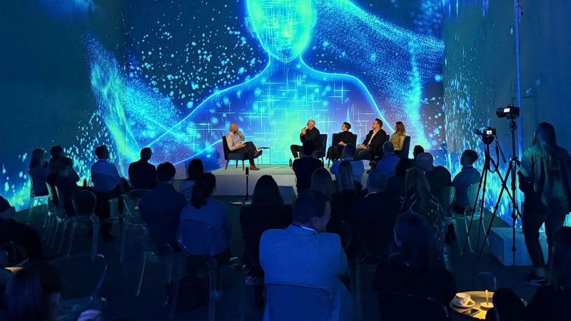 Panel discussion on stage with a crowd of people and an immersive digital background